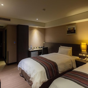 A hotel room with two beds, a desk, a chair, a lamp, and a painting on the wall. - Royal Guest Hotel (Tainan)