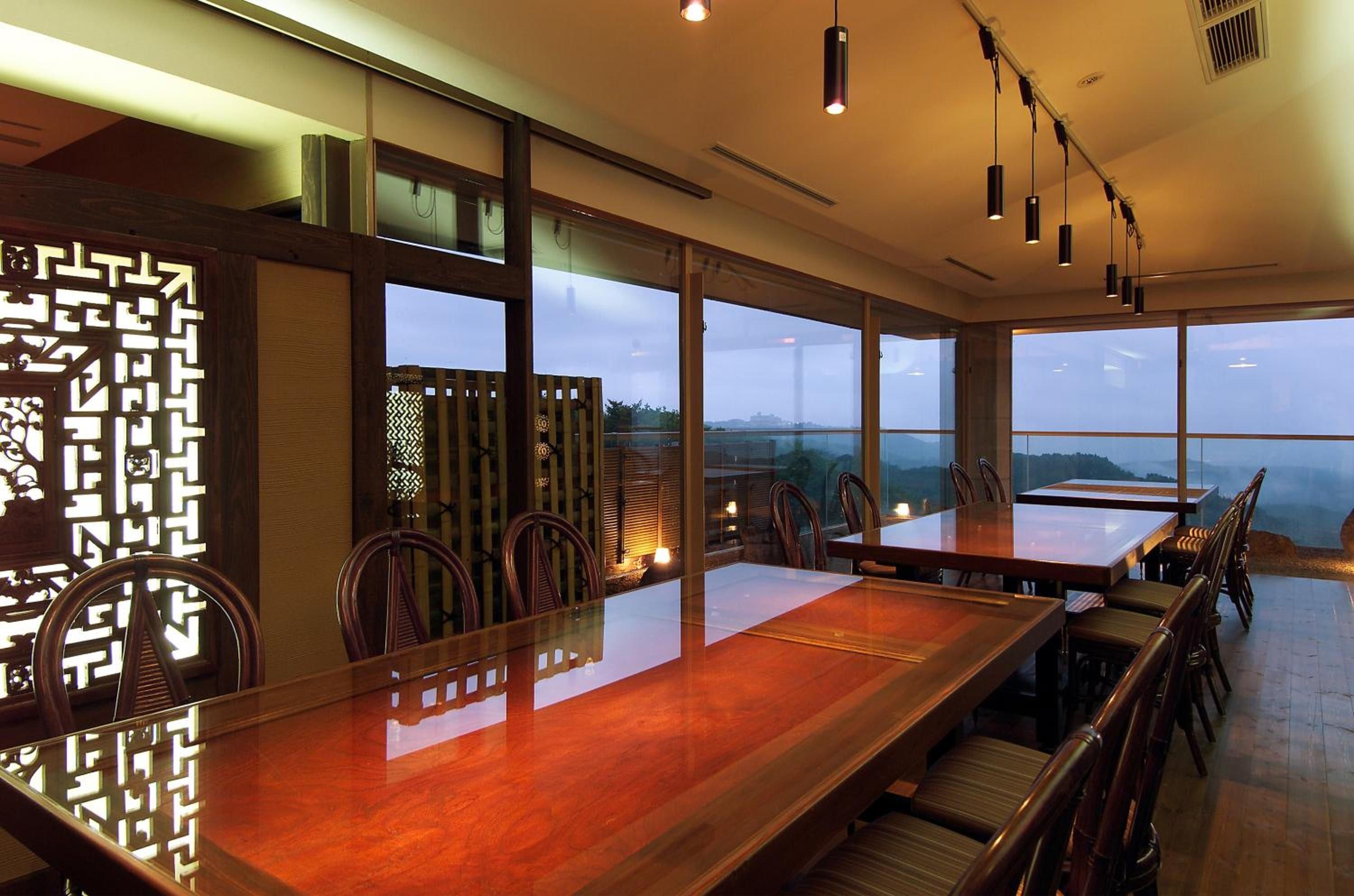 Un comedor con una larga mesa de madera, sillas y vistas al exterior a través de amplios ventanales.