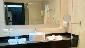 Un baño moderno con un espejo grande, un lavabo y una cabina de ducha de vidrio.