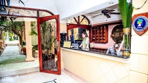 Una zona de recepción con mostrador, un espejo decorativo y un cartel.