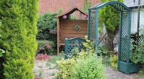A garden with a wooden shed, a green arbor, and a variety of plants. - Remarc Guest House (Bishop's Stortford)