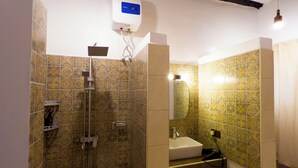 Un baño con baldosas estampadas, ducha, lavabo e inodoro.