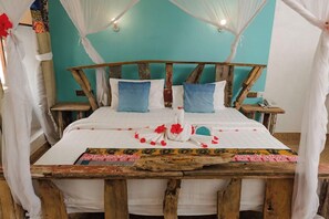 A bed with a wooden headboard, white bedding, and a decorative pillow arrangement. - Zanzi House (Zanzibar Town)