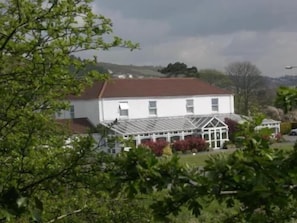 A white building with a glass conservatory and a red roof. - Ashburnham Hotel (Burry Port)