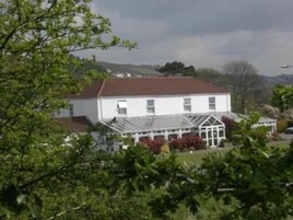 A white building with a glass conservatory and a red roof.