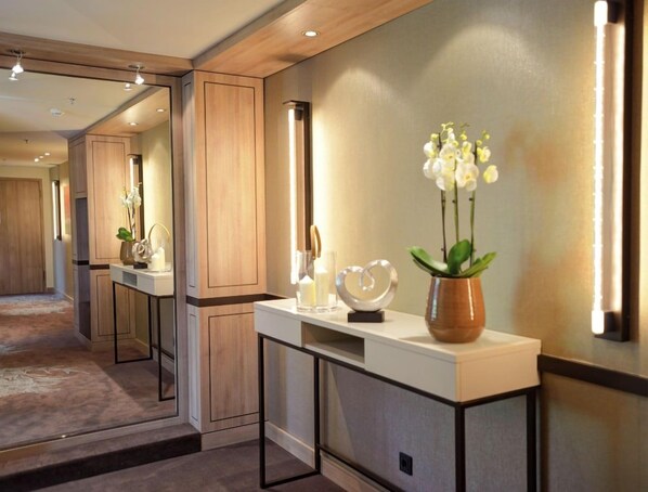 A hotel reception area with a reception desk, a mirror, and a vase with flowers. - Favorite Parkhotel (Mainz)
