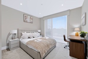 A modern bedroom with a large bed, bedside tables, a desk, and a chair. - Modern 2 Bed Battersea Retreat Next to the Park (London)