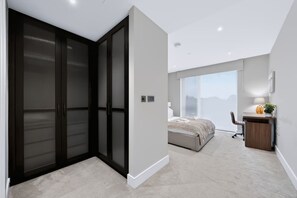A modern bedroom with a large bed, a desk, and a view through a window. - Modern 2 Bed Battersea Retreat Next to the Park (London)