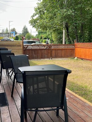 Een terras met tafels en stoelen, een houten terras en een houten omheining.