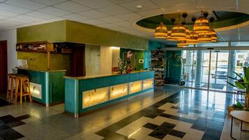 Eine Hotelhalle mit einer Rezeption, einer Bar und einer Sitzgelegenheit.