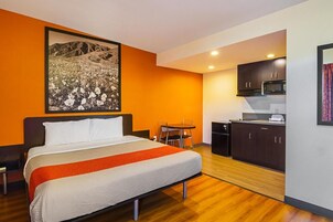 A hotel room with a bed, a dining table, and a kitchenette.