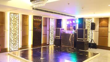 A spacious room with a large black floor, a chandelier, and a bar area with speakers.