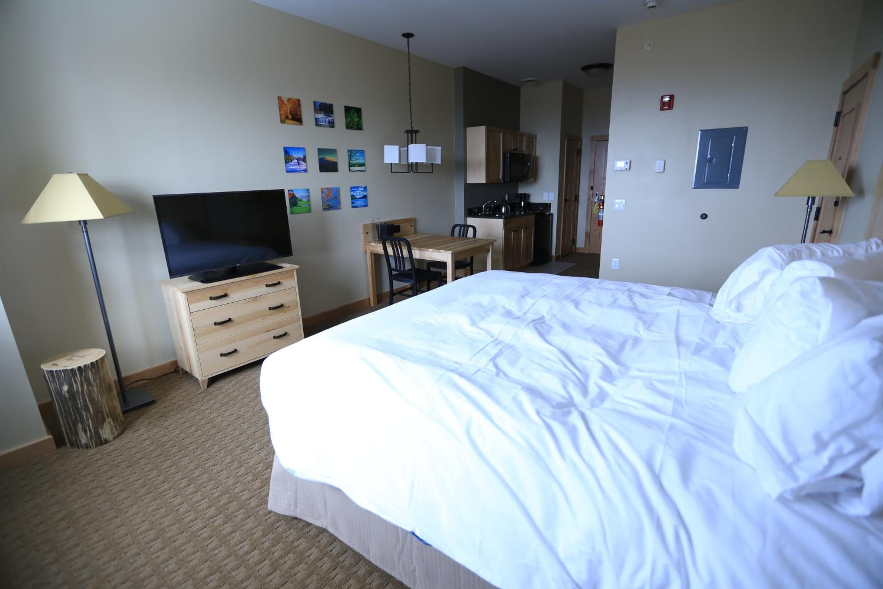 Ein Hotelzimmer mit Bett, Schreibtisch, Fernseher, Kleiderschrank und einer Küchenzeile.