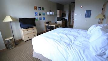 A hotel room with a bed, a desk, a television, a wardrobe, and a kitchenette.