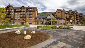 Un hôtel moderne à plusieurs étages, doté de balcons, et comprenant une cour intérieure aménagée ainsi qu’un espace de stationnement.