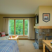 Una habitación de hotel con un ventanal grande, una chimenea, un televisor y un comedor.