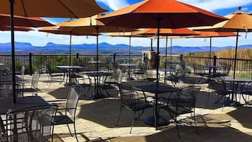 An outdoor patio with tables and chairs, umbrellas, and a view of distant mountains.