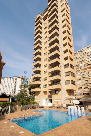A high-rise hotel with a swimming pool, multiple balconies, and a clear sky. - Torre San Diego (Benidorm)