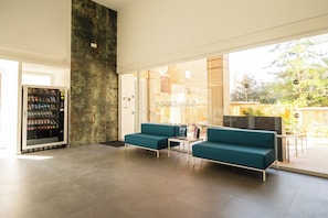A modern lobby with a seating area, a vending machine, and a glass door leading outside. - Torre San Diego (Benidorm)