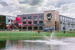A building with a large mural of a pink octopus, a wooden sign with a dog logo, and a sign for Doghouse Hotel & Brewery.