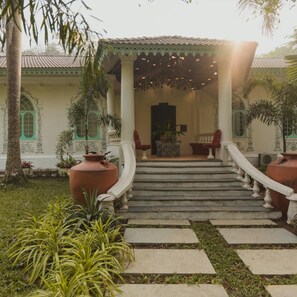 A building with a covered entrance, steps leading up to it, and a garden with potted plants. - Brij Casa Susegad, Goa (Loutolim)