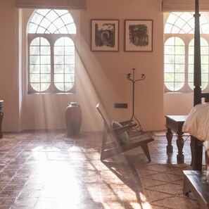 A room with a large window, a chair, a bed, a vase, and two framed pictures on the wall. - Brij Casa Susegad, Goa (Loutolim)