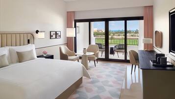 Hotelkamer met een groot bed, een bureau, een stoel, een tafeltje en een balkon met uitzicht.