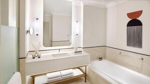 Uma casa de banho moderna com banheira, espelho sobre a toucador e porta-toalhas.
