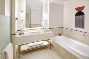 Une salle de bain moderne avec une baignoire, un meuble-lavabo avec un miroir et un porte-serviettes.