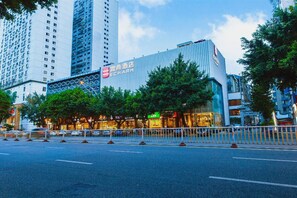 A modern hotel with a prominent sign, surrounded by tall buildings and trees. - Echarm Hotel Sanfang Qixiang Dongjiekou (Fuzhou)