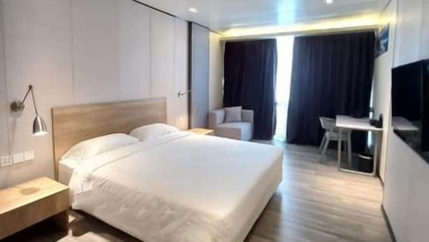 A modern hotel room with a large bed, bedside tables, a desk, and a flat-screen TV. - Samanea Boutique Apartment (Tangerang)