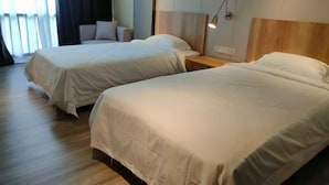 A hotel room with two beds, a nightstand, a wall-mounted lamp, and a window with curtains. - Samanea Boutique Apartment (Tangerang)