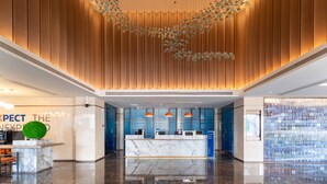 Eine moderne Lobby mit einer Rezeption, einer grünen, kugelförmigen Dekoration und einem außergewöhnlichen Deckengestalt.