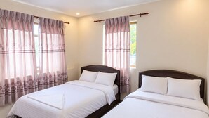Habitación de hotel con dos camas, cabecero de madera y piso alfombrado.