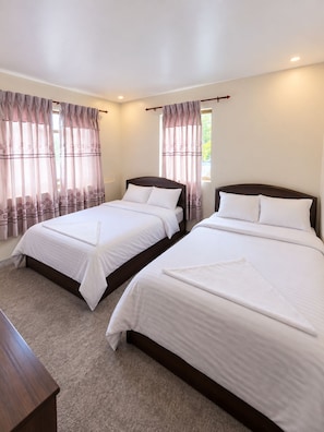 Ein Hotelzimmer mit zwei Betten, einem Holzkopfteil und Teppichboden.