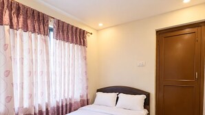 Un dormitorio con una cama individual, una puerta de madera y suelo alfombrado.
