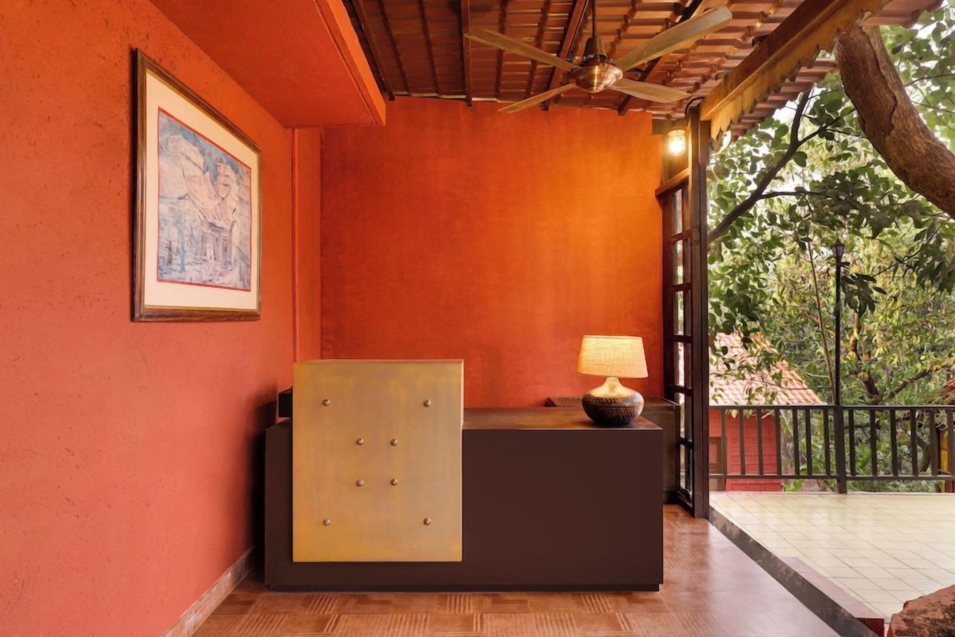Un área de recepción con techo de madera, una obra de arte enmarcada en la pared, un mostrador de recepción con lámpara y vista a los árboles.