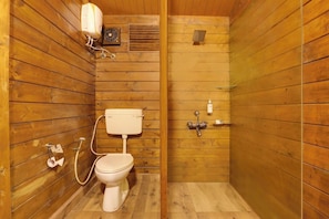 Un baño con paneles de madera, un inodoro, una ducha y un secador de manos.