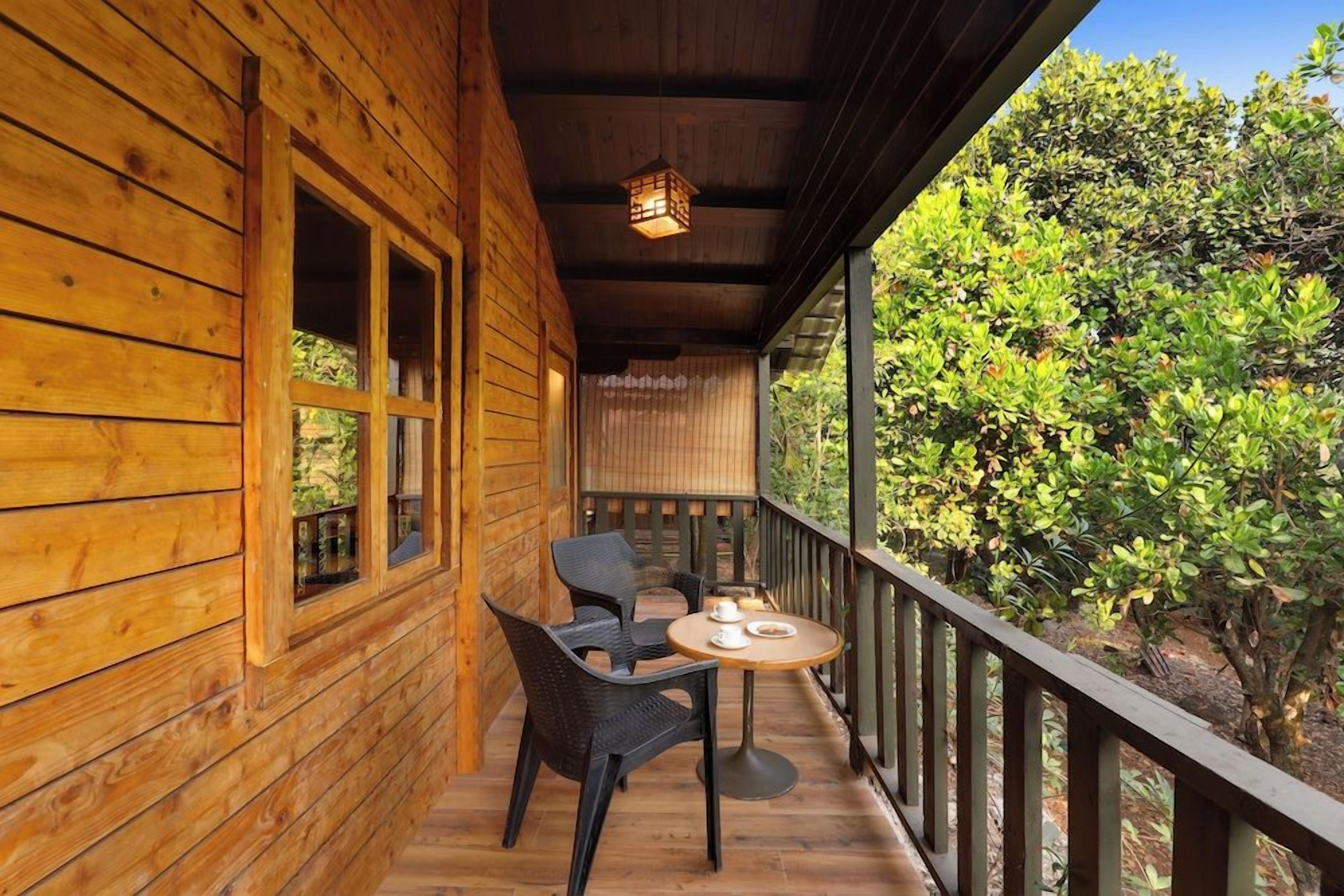 Una terraza de madera con una mesa y sillas, con vistas a un jardín exuberante.