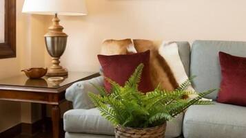 A living room with a sofa, a lamp, a coffee table with a book and a plant, and framed pictures on the wall.