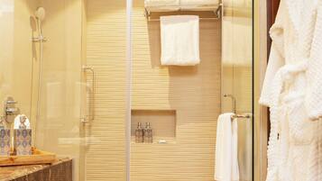 A modern bathroom with a glass shower enclosure, a marble countertop, and a wooden door.