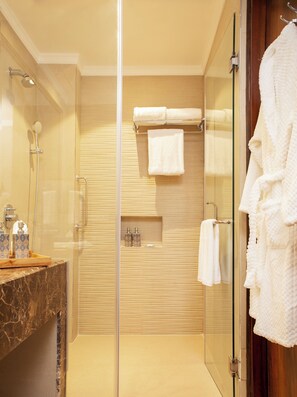 Un baño moderno con cabina de ducha de vidrio, encimera de mármol y puerta de madera.