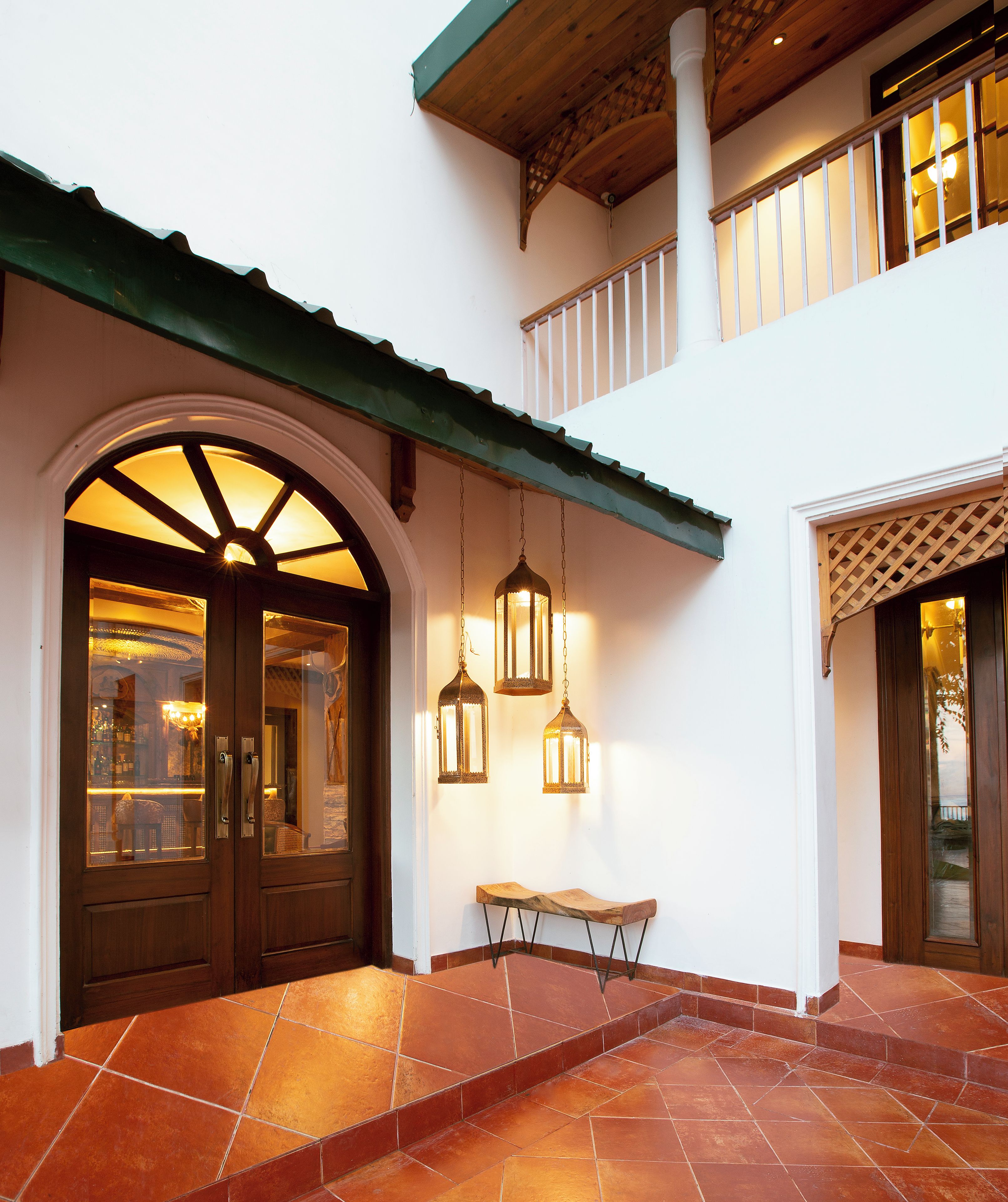 A building entrance with a wooden door, a bench, and hanging lanterns.