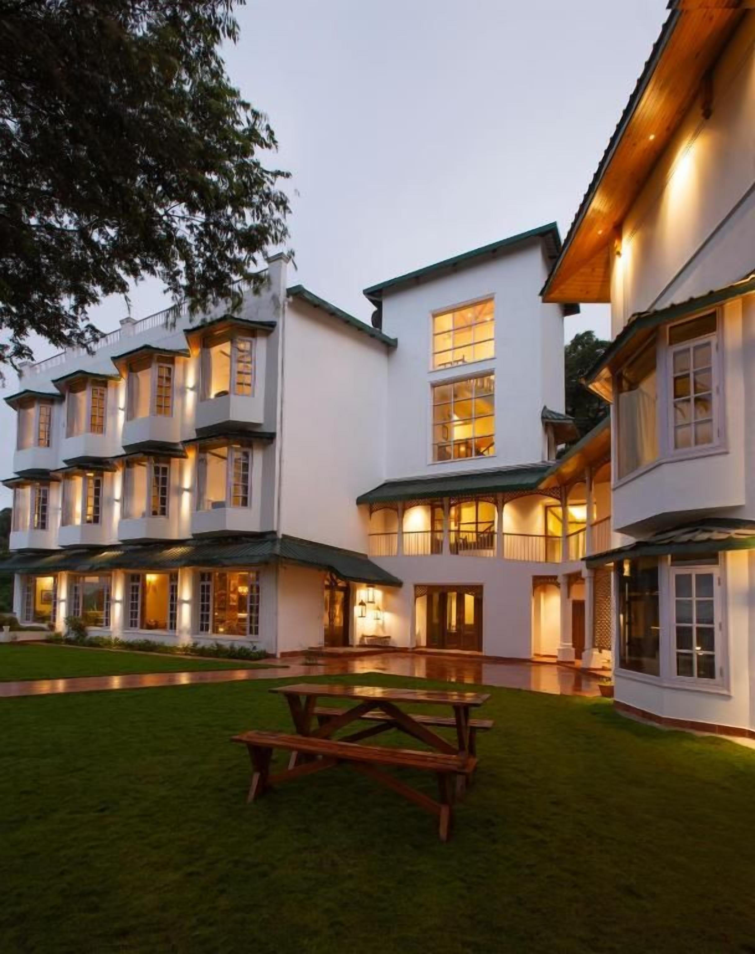 Un edificio de varios pisos con un patio, iluminación exterior y una mesa de picnic.