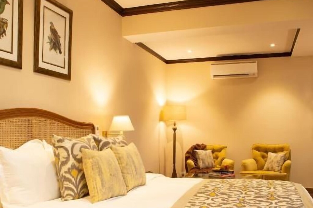 Habitación de hotel con una cama grande, dos lámparas de noche, una silla y un aire acondicionado de pared.