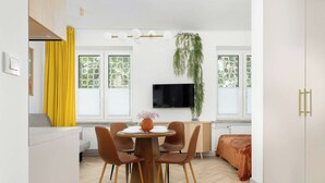Une cuisine moderne avec un coin repas, un téléviseur à écran plat fixé au mur et une plante suspendue.