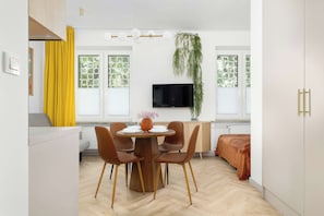 Een moderne keuken met een eethoek, een flatscreen televisie aan de muur en een hangplant.