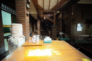 A hotel room with a wooden table, a brick wall, and a window with a view.
