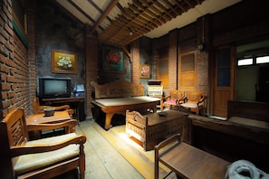 Una habitación acogedora con pared de ladrillo, muebles de madera, televisor y una mesa.