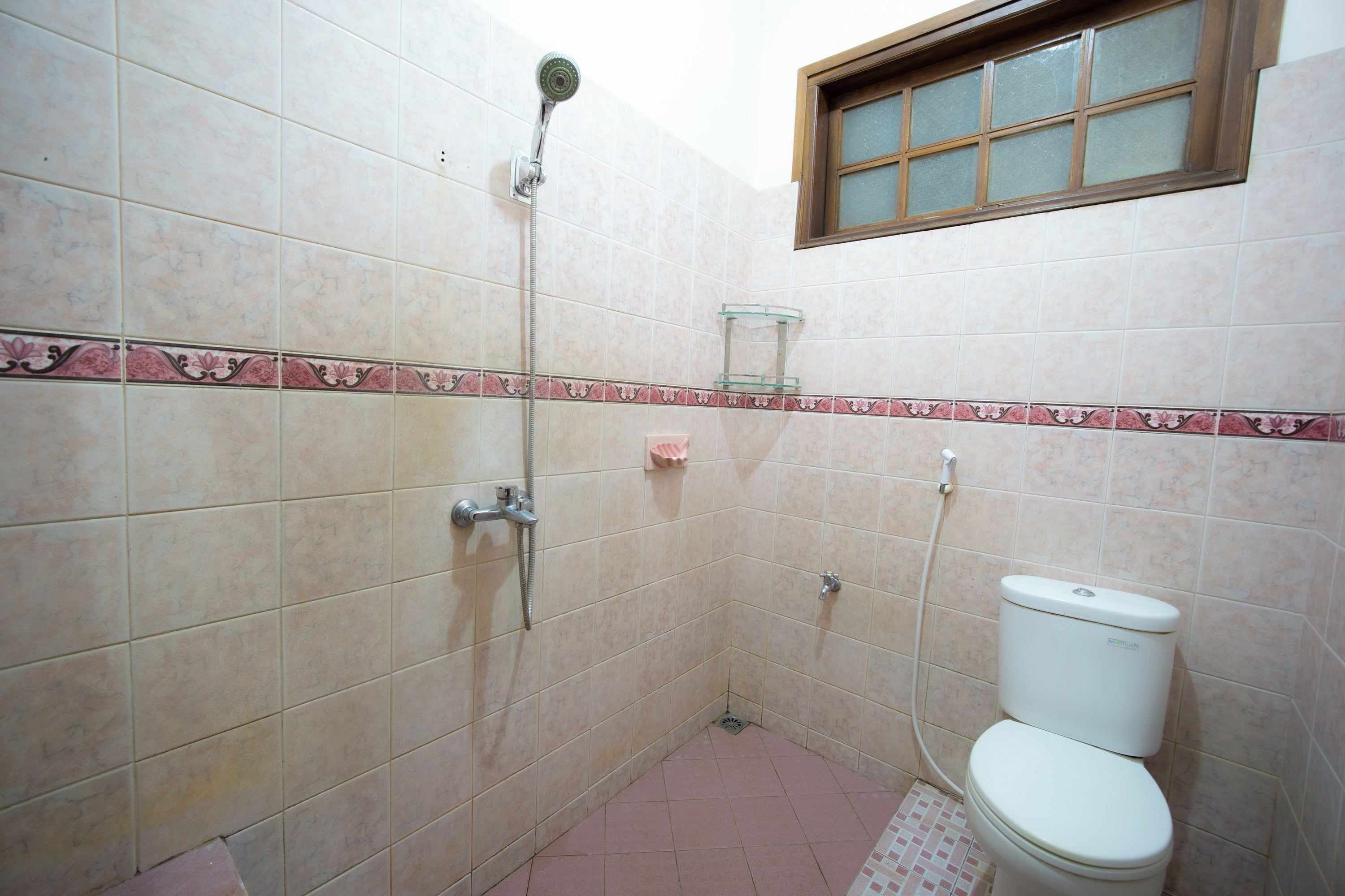 A bathroom with a toilet, a shower, and a window.